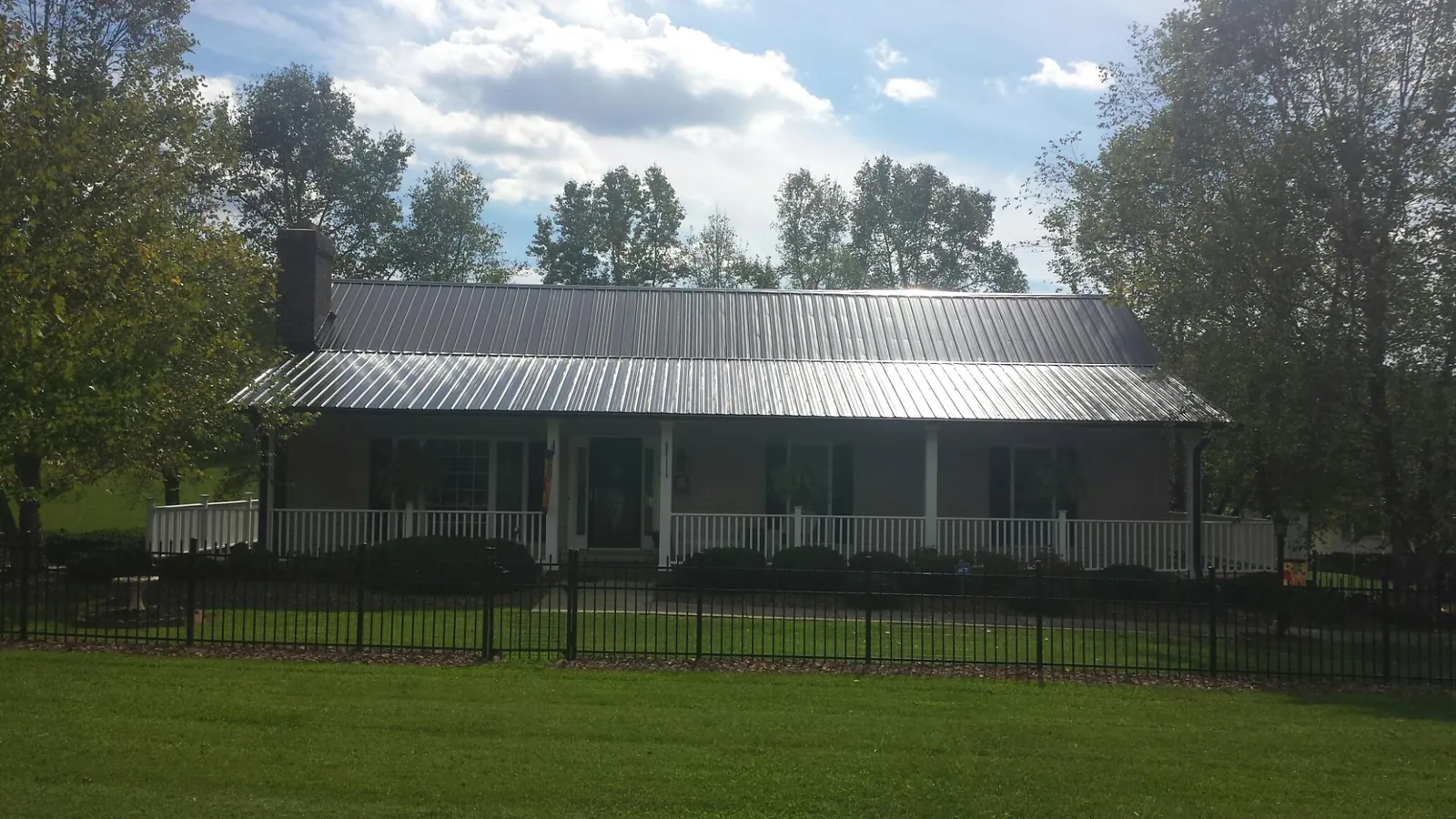 Gray metal roof on a brick ranch with a full width front porch — Gutter Guard Installation work by our crew in Ray