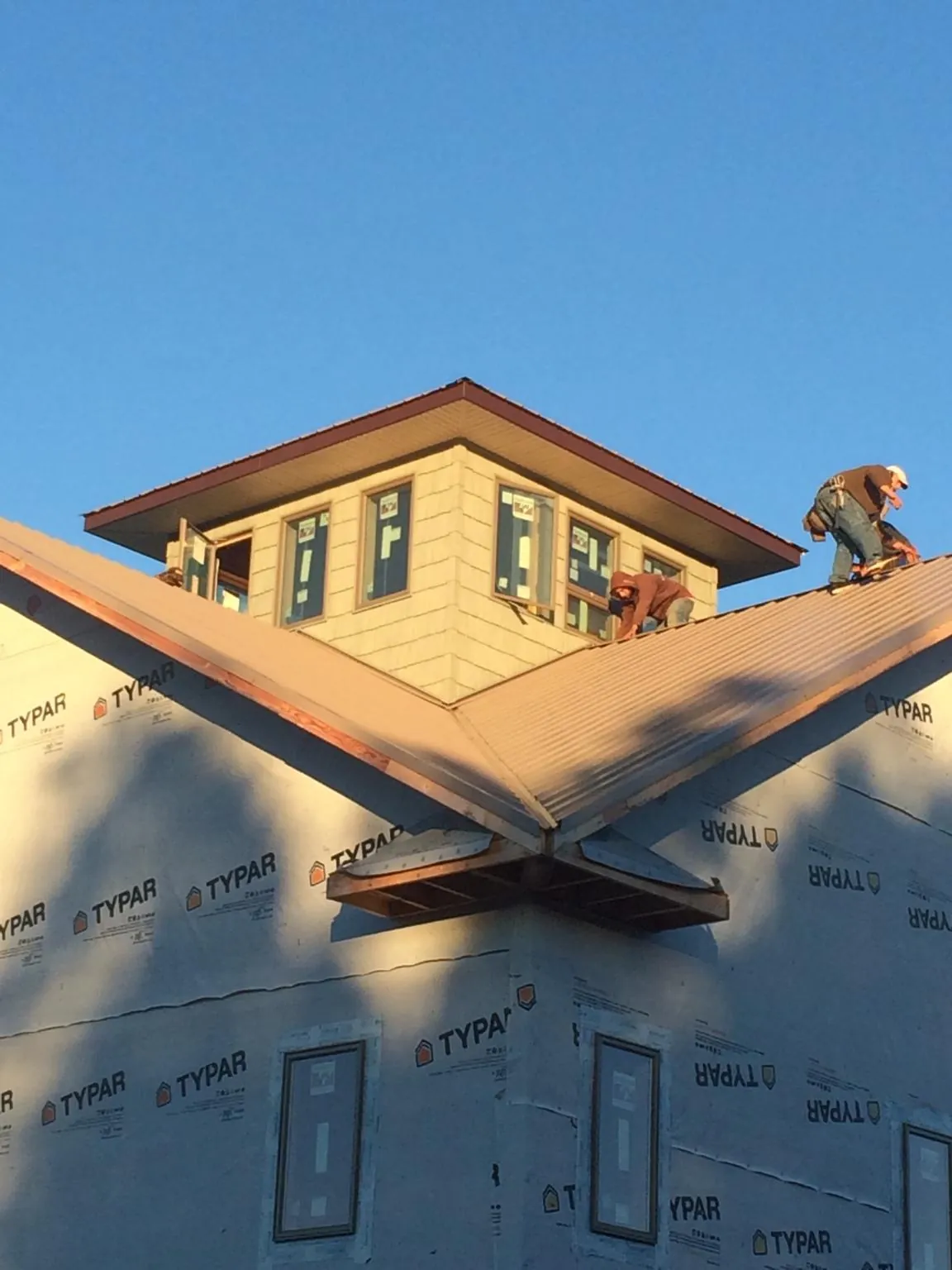 Roofers working around a rooftop cupola on a new metal roof at sunset — Roof Waterproofing in Ray by Roofing Brothers